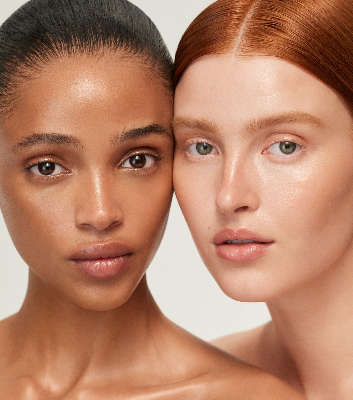 Two women with different skin tones standing close together against a neutral background