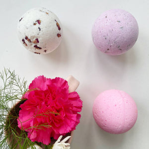 A group of three soak bath bombs with a pink carnation flower