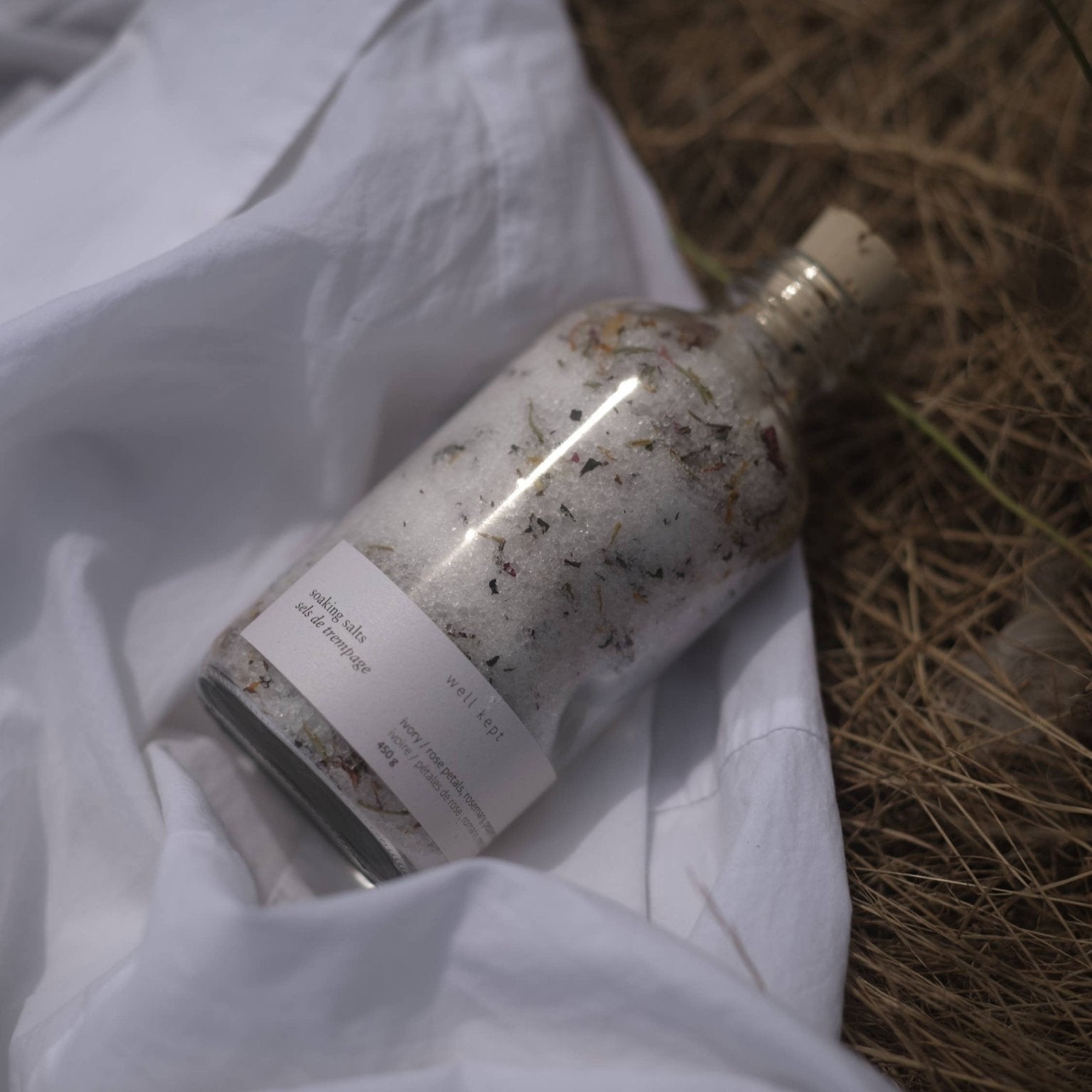Glass bottle with natural elements on a white fabric background