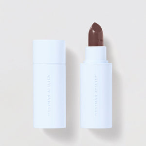 White cosmetic stick with brown applicator on a light gray background