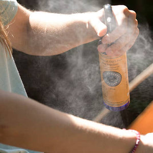 Person using a spray bottle with a visible label, likely outdoors.