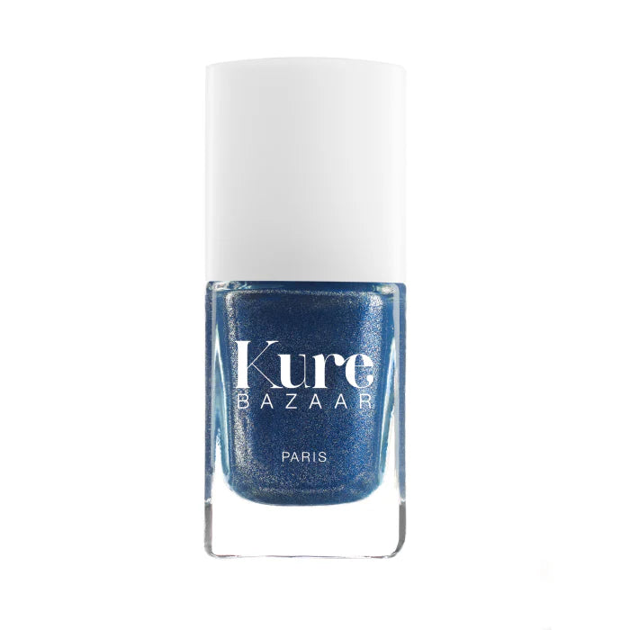 A bottle of Kure Bazaar nail polish in a blue shade with a metallic finish, displayed against a white background.