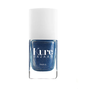 A bottle of Kure Bazaar nail polish in a blue shade with a metallic finish, displayed against a white background.