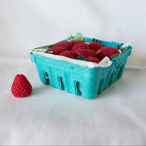 A set of Happy Organics Strawberry Beeswax Birthday Candles in a green produce box.