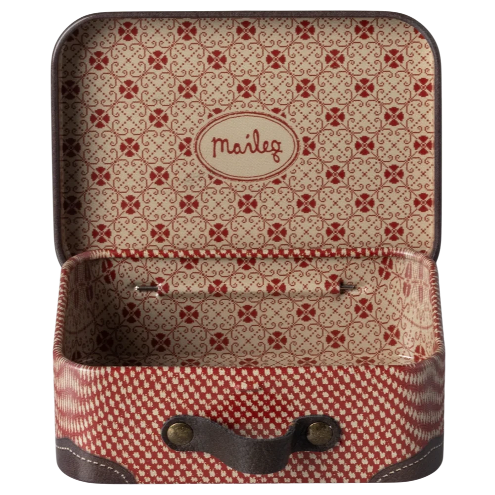 Small metal suitcase with a red and beige checkered pattern and decorative travel stickers such as 'Hotel Chatham Paris' and 'Bagage Room'.