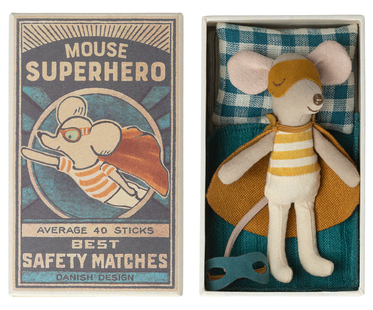 A toy mouse figurine dressed as a superhero, with a yellow and gray costume, inside a red and blue patterned matchbox. The matchbox lid has an illustration of the same mouse in action pose with text 'Mouse Superhero' and the text 'Average 40 Sticks Best Safety Matches Danish Design'.
