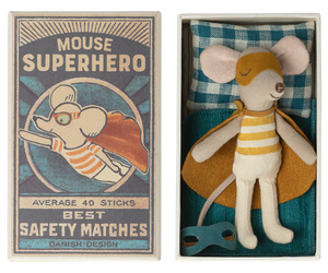 A toy mouse figurine dressed as a superhero, with a yellow and gray costume, inside a red and blue patterned matchbox. The matchbox lid has an illustration of the same mouse in action pose with text 'Mouse Superhero' and the text 'Average 40 Sticks Best Safety Matches Danish Design'.