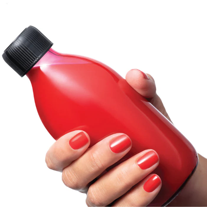 A person holding a bottle with red liquid contents. 