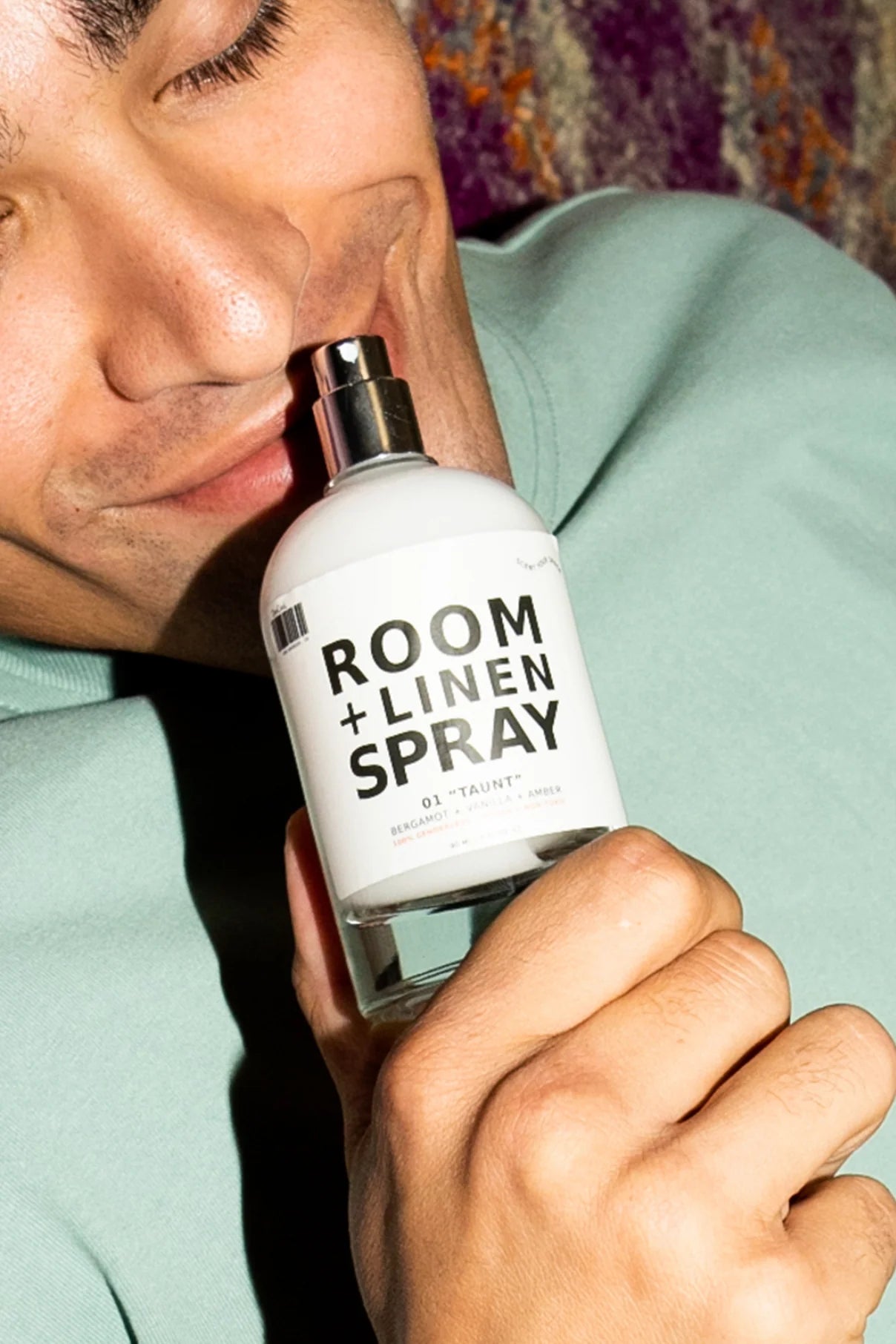 Person holding a bottle of room and linen spray with a neutral background