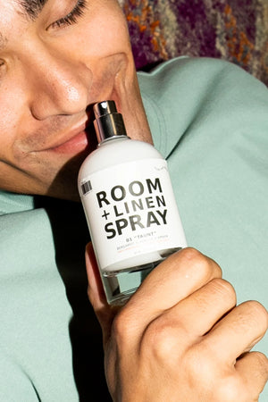 Person holding a bottle of room and linen spray with a neutral background