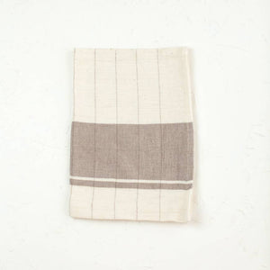 A brown and cream colored tea towel on a white background. 