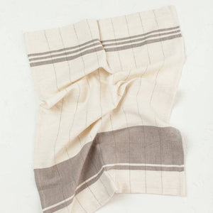 A brown and cream colored tea towel on a white background. 