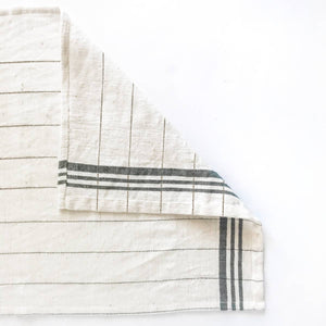 A green and cream colored tea towel on a white background. 