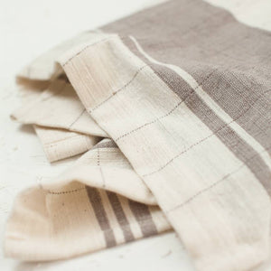 A brown and cream colored tea towel on a white background. 