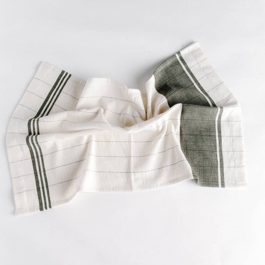A green and cream colored tea towel on a white background. 