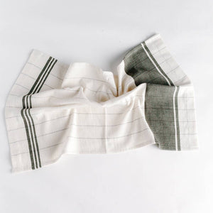 A green and cream colored tea towel on a white background. 