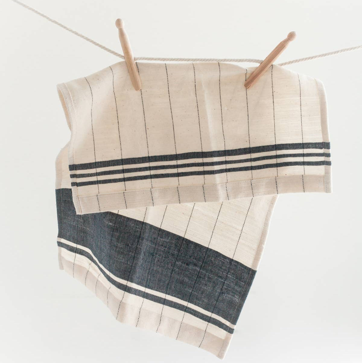 A blue and cream colored tea towel on a white background. 