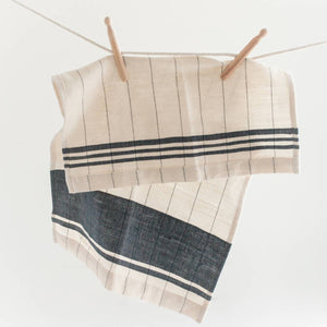 A blue and cream colored tea towel on a white background. 