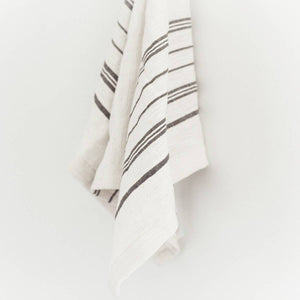 A white tea towel with grey stripes on a white background. 