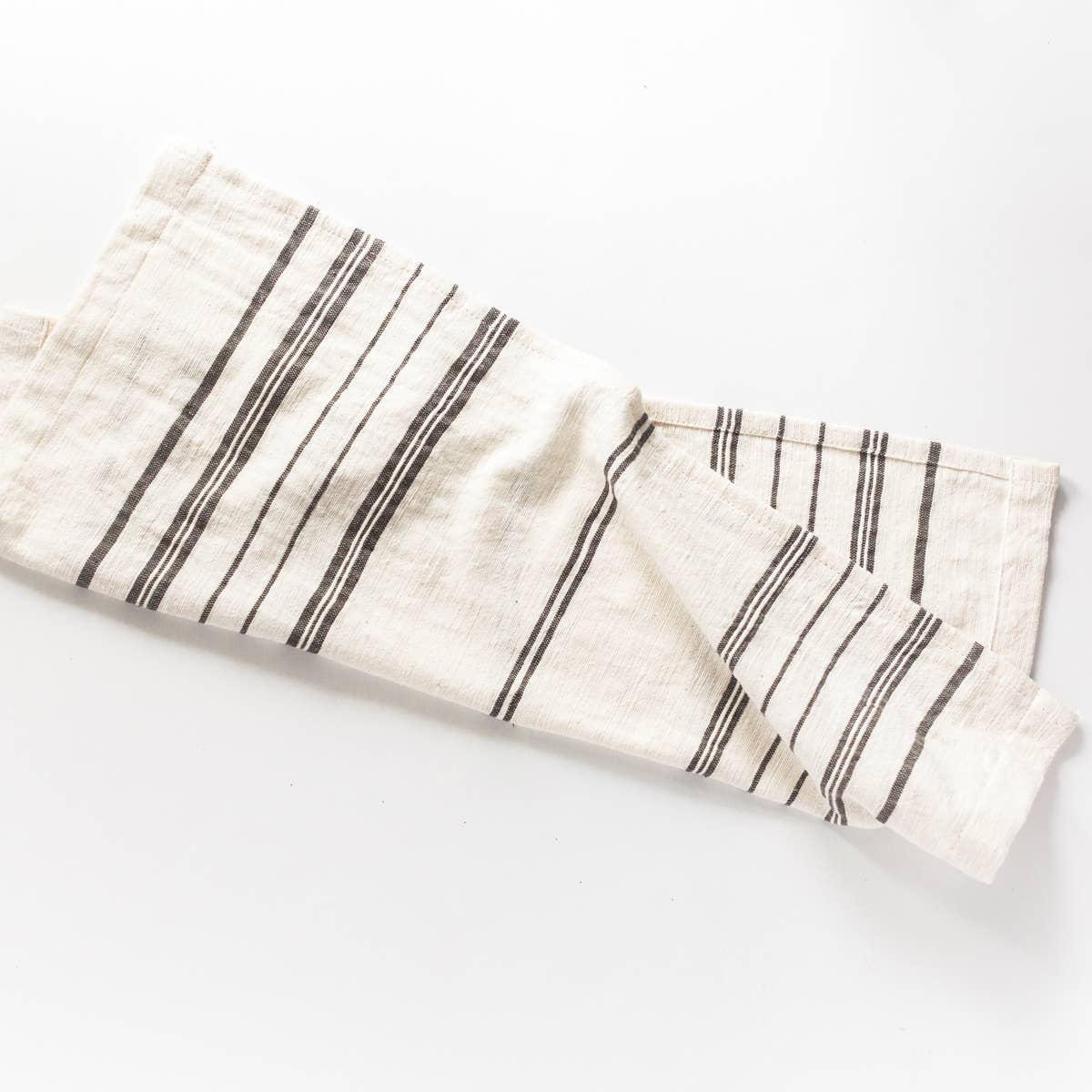 A striped cotton tea towel laid out on a surface, with black stripes on a cream background.