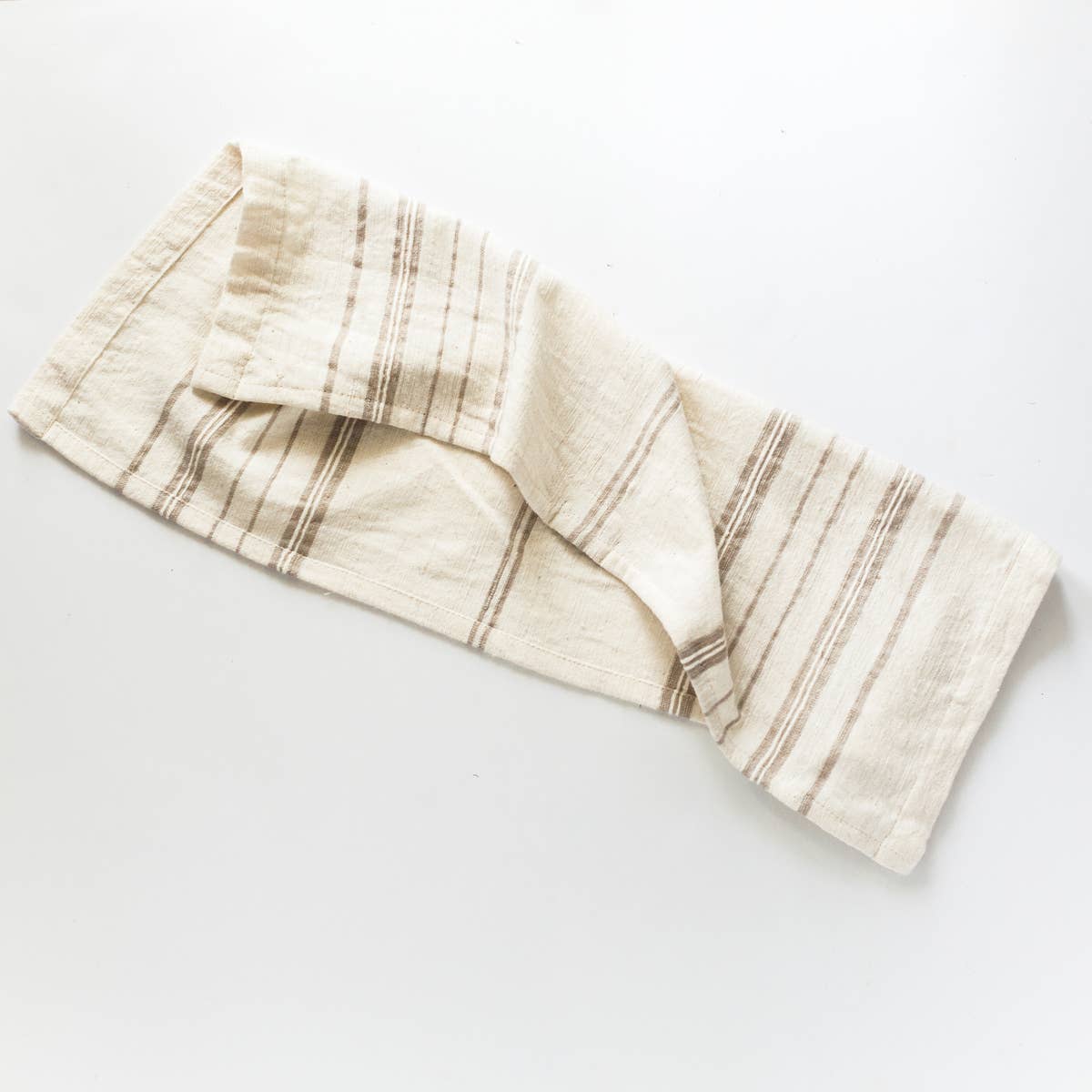 A white tea towel with brown stripes on a white background. 