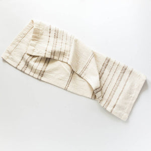 A white tea towel with brown stripes on a white background. 