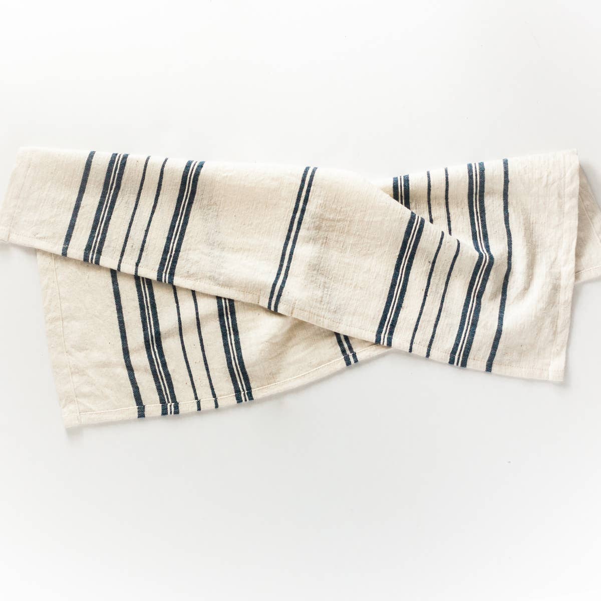 A white tea towel with blue stripes on a white background. 