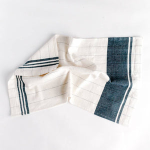 A blue and cream colored tea towel on a white background. 