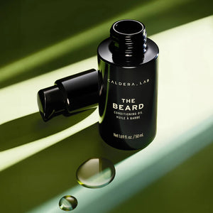 An open bottle of the beard conditioning oil, with drops of product in the foreground. 