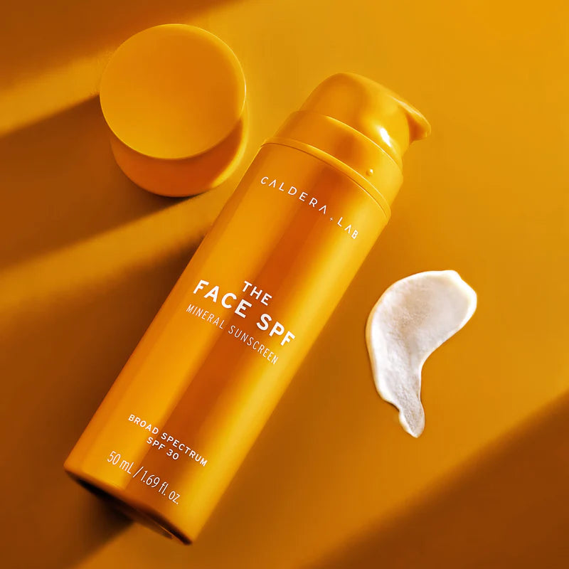A bottle of the face spa, on an orange surface. 