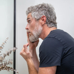 A man looks at his face in the mirror. 