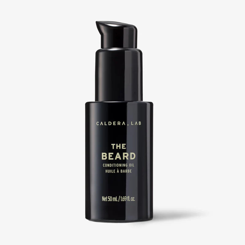 A black pump bottle labeled 'THE BEARD' by Caldera + Lab, which is a conditioning oil for beard and skin.