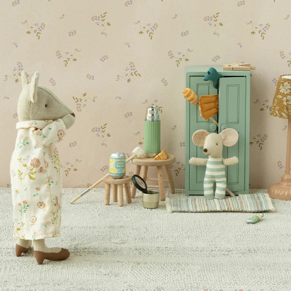 Two toy mice in a room with floral wallpaper, a lamp, and small furniture.