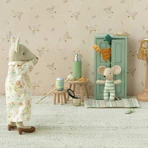 Two toy mice in a room with floral wallpaper, a lamp, and small furniture.