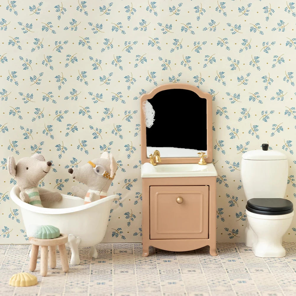 Miniature bathroom set with toys in a bathroom with floral wallpaper.