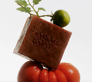A tomato soap brick stacked between two tomatoes. 