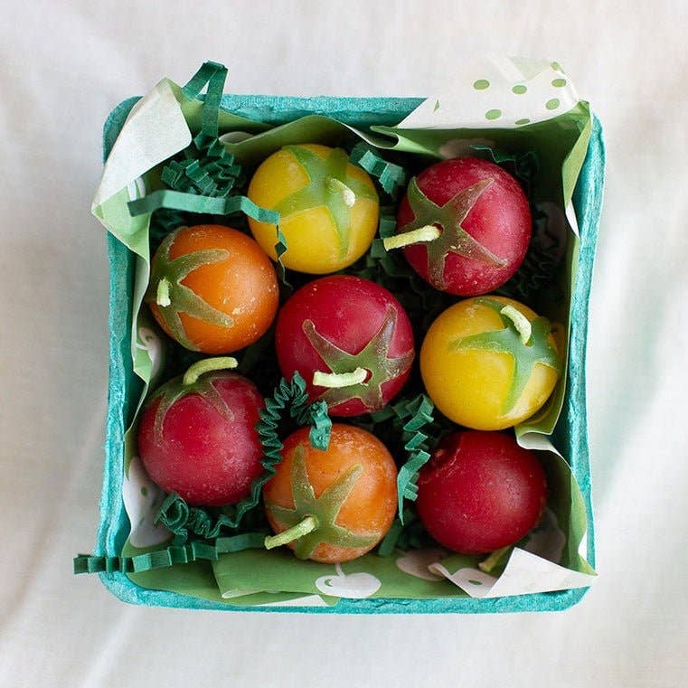 Colorful tomato-shaped candles in a box on a white background
