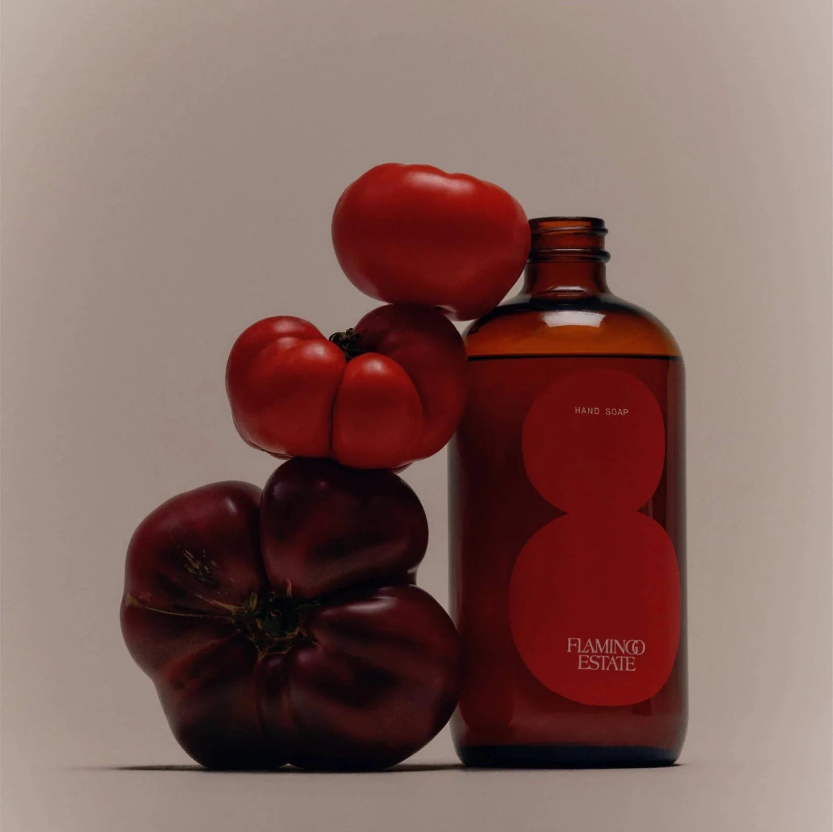 A brown glass bottle of Flamingo Estate tomato hand soap with three red tomatoes