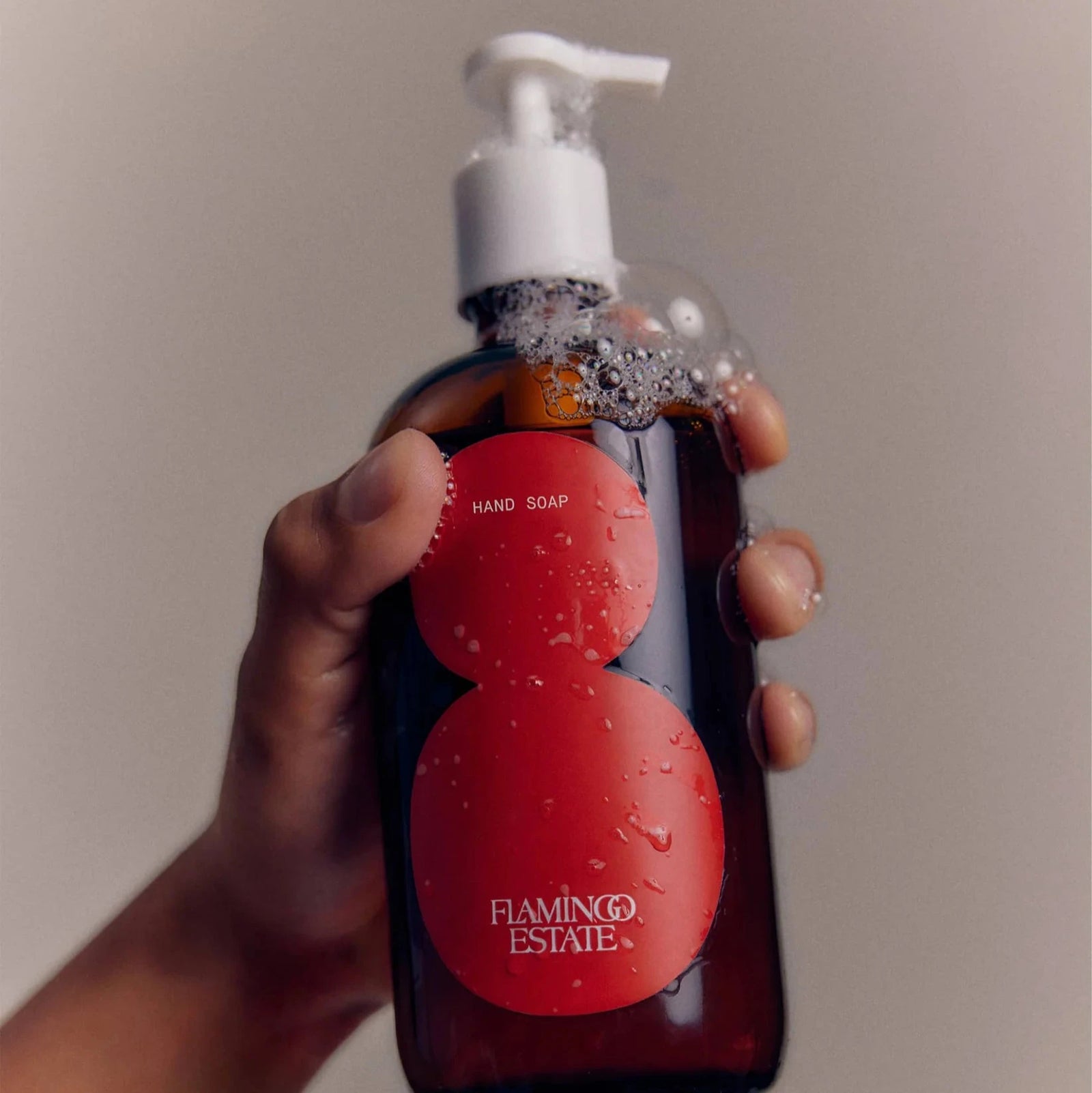 A brown glass bottle of Flamingo Estate tomato hand soap with a white cap