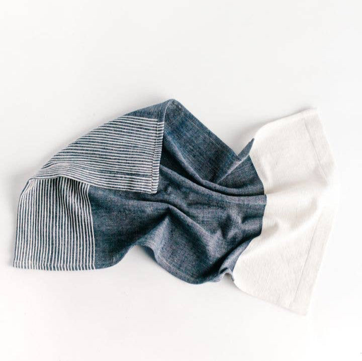 A folded striped tea towel in gray and white, with visible ribbed texture and sewn edges.