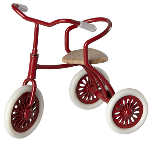 A red tricycle with wooden seat and rubber wheels, designed for young children.