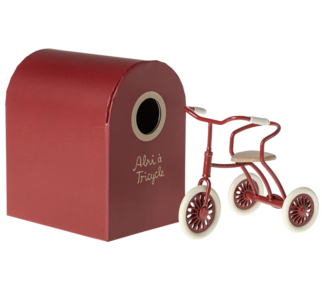 A red tricycle with wooden seat and rubber wheels, designed for young children.