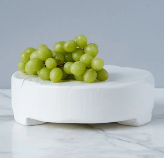 A white trivet with grapes on it. 