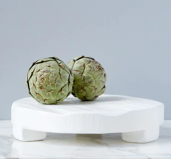 A white trivet with grapes on it. 