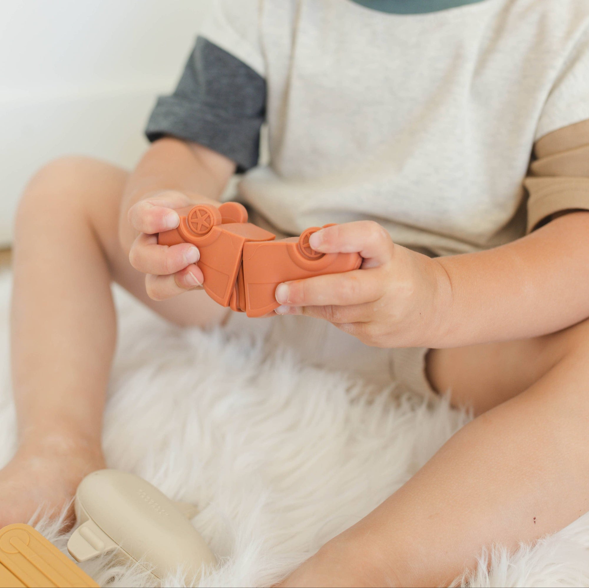 A small child puts together two pieces of a bath toy vehicle. 