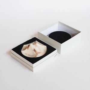 A light grey box with a beige and white architectural soap. 