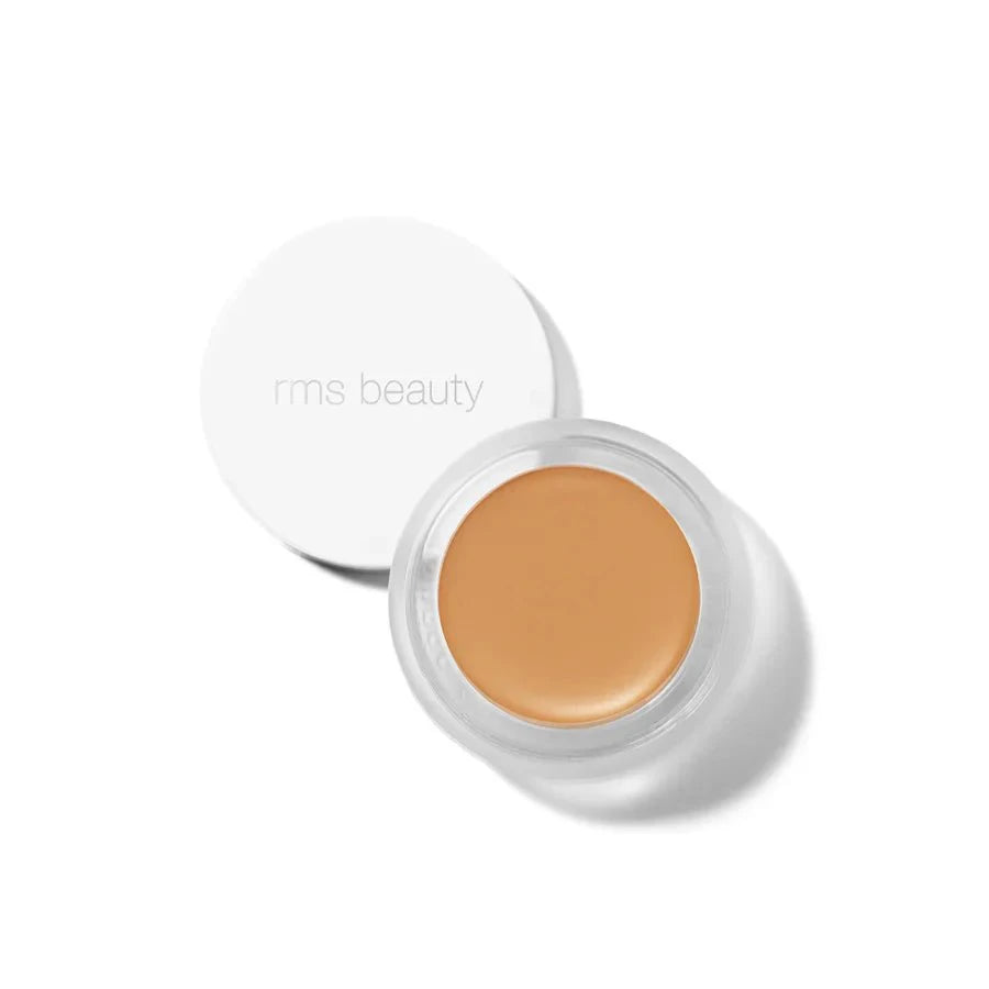 A small glass pan of RMS Beauty UnCoverup Concealer with a white cap that says "RMS Beauty,"