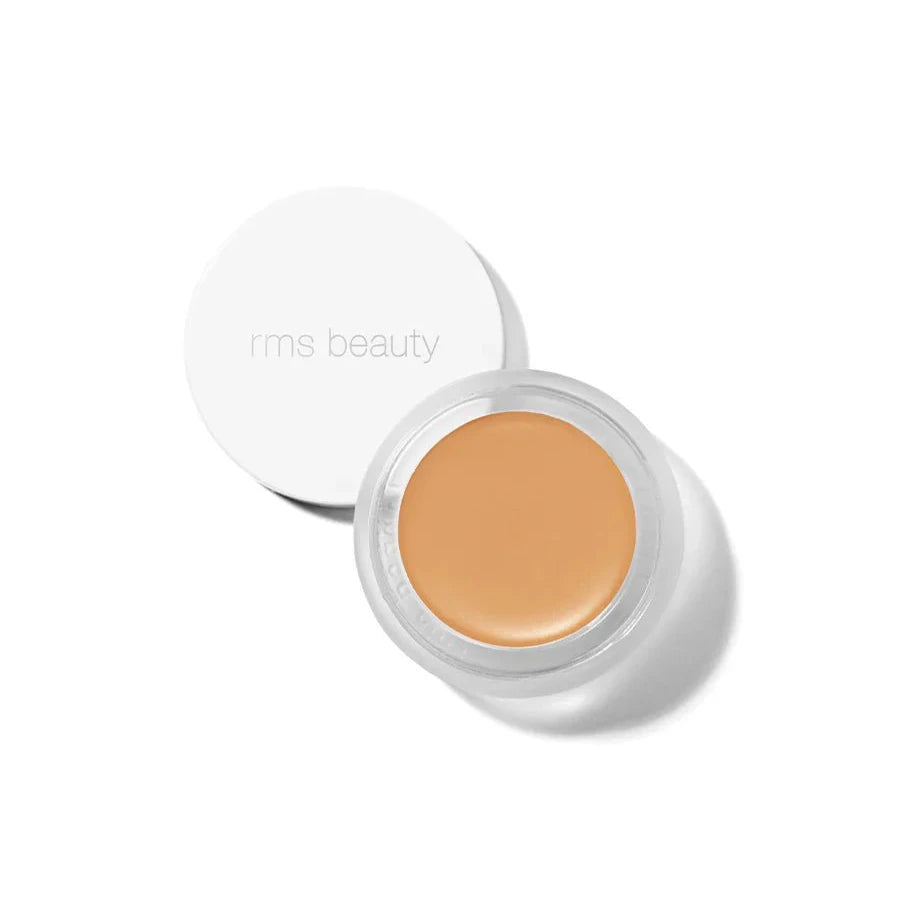 A small glass pan of RMS Beauty UnCoverup Concealer with a white cap that says "RMS Beauty,"