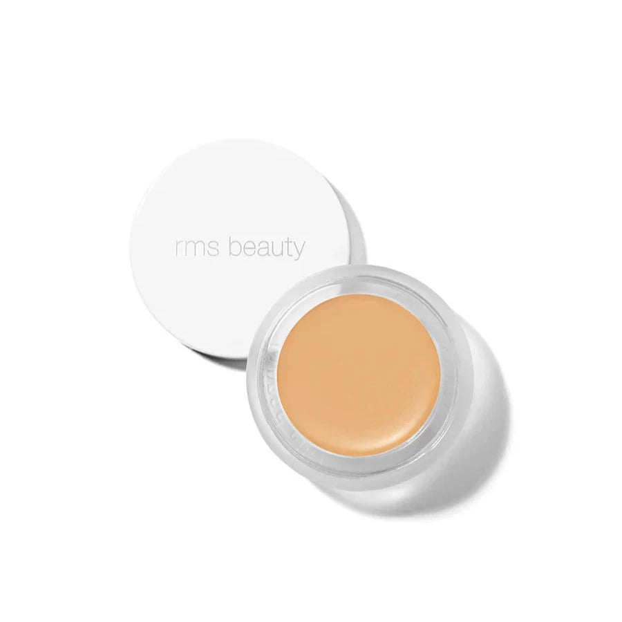A small glass pan of RMS Beauty UnCoverup Concealer with a white cap that says "RMS Beauty,"