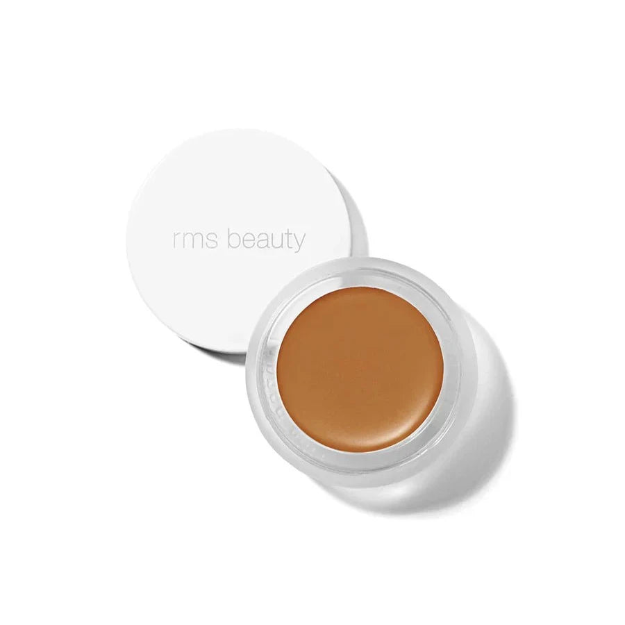 A small glass pan of RMS Beauty UnCoverup Concealer with a white cap that says "RMS Beauty,"